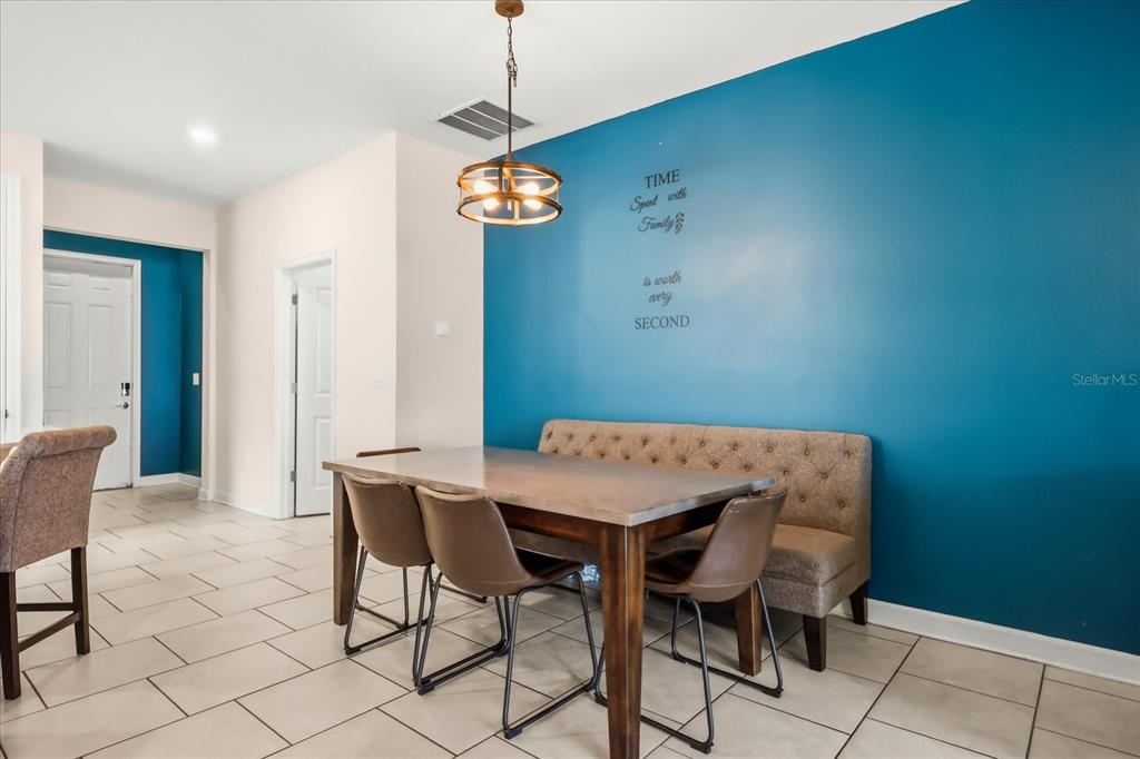 A dining area features a wooden table, a tufted bench, and chairs against a blue wall — 133 TAFT DRIVE, DAVENPORT, FL