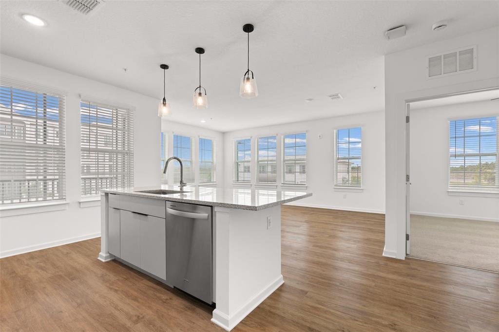 A kitchen island with a stainless steel dishwasher sits in a bright, open-concept living space — 1700 RANCH ROAD UNIT C1-7213, NOKOMIS, FL
