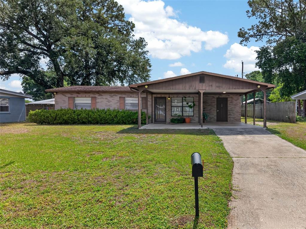 A single-story brick house features a front porch, a carport, and a large grassy lawn — 3004 DREWERY AVENUE, LAKELAND, FL
