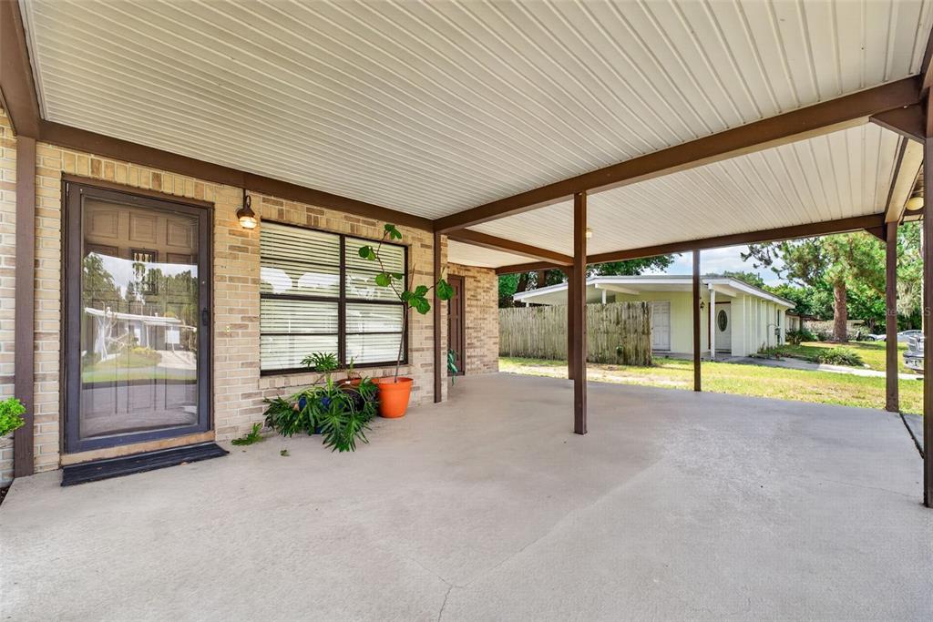A concrete carport with a white ceiling and brown support beams attached to a house — 3004 DREWERY AVENUE, LAKELAND, FL