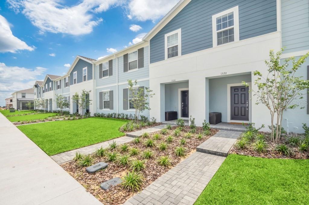 A row of two-story townhomes with blue siding, white trim, and paved walkways — 1320 LAVA TREE DR, DAVENPORT, FL