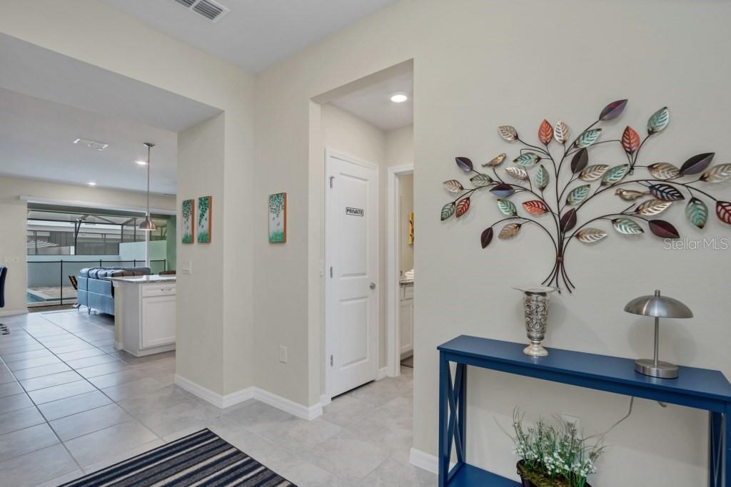 A hallway with tile flooring leads to a kitchen and living area with pool access — 1320 LAVA TREE DR, DAVENPORT, FL