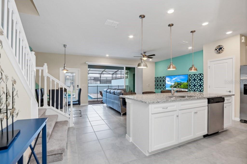A kitchen with a granite island and white cabinets overlooks a living area and pool — 1320 LAVA TREE DR, DAVENPORT, FL