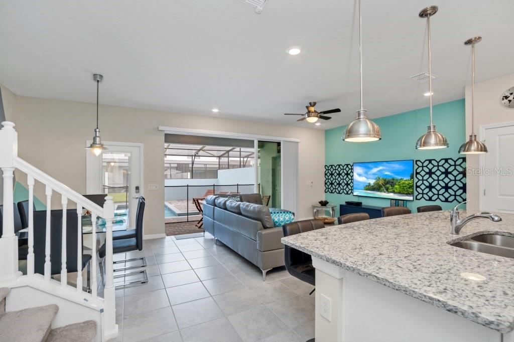 An open-concept living area features a kitchen island, dining space, and a view of a pool — 1320 LAVA TREE DR, DAVENPORT, FL
