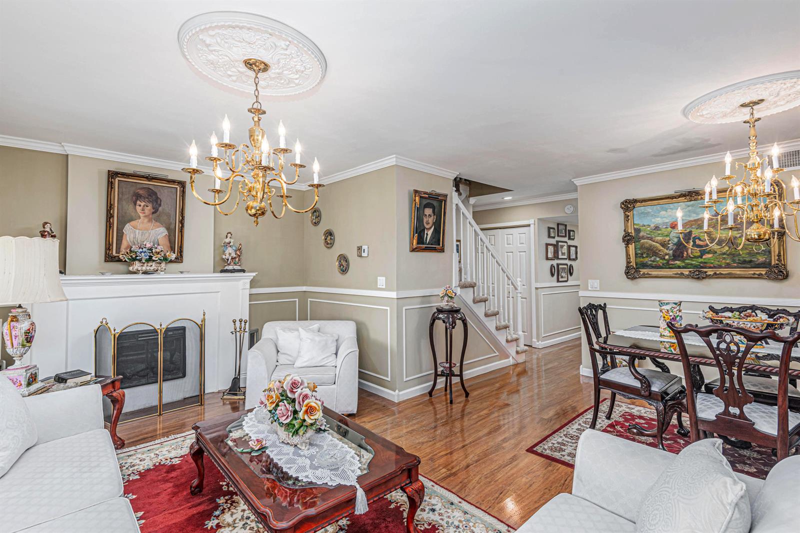 A living and dining room features hardwood floors, two crystal chandeliers, and a fireplace — 18560 SE Wood Haven Lane # G, Jupiter FL 33469, JUPITER, FL