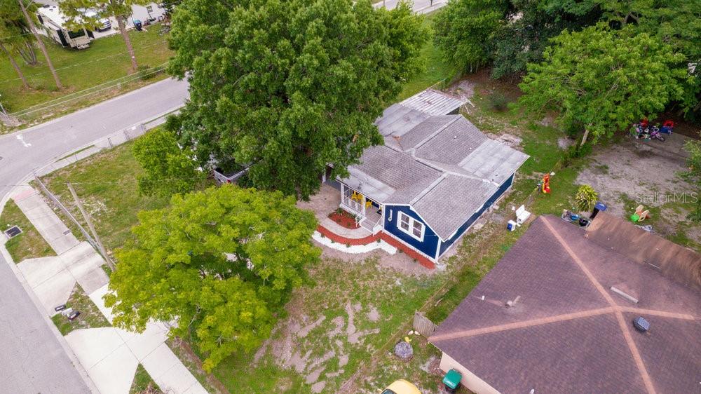 An aerial view shows a blue house with a gray roof surrounded by large trees — 7524 MARIETTA STREET, ORLANDO, FL