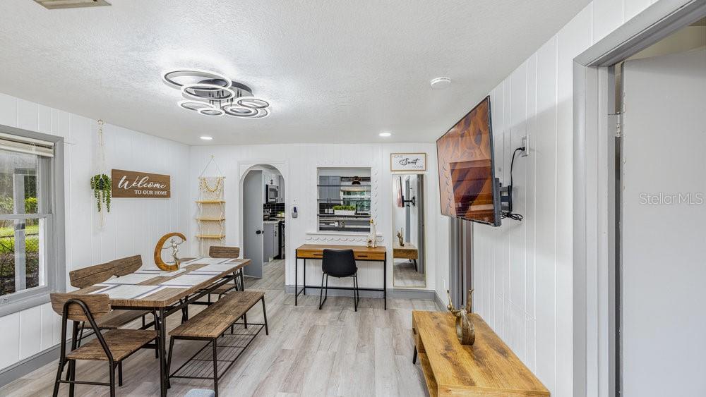 A dining room features a wooden table with benches, a desk, and a wall-mounted television — 7524 MARIETTA STREET, ORLANDO, FL