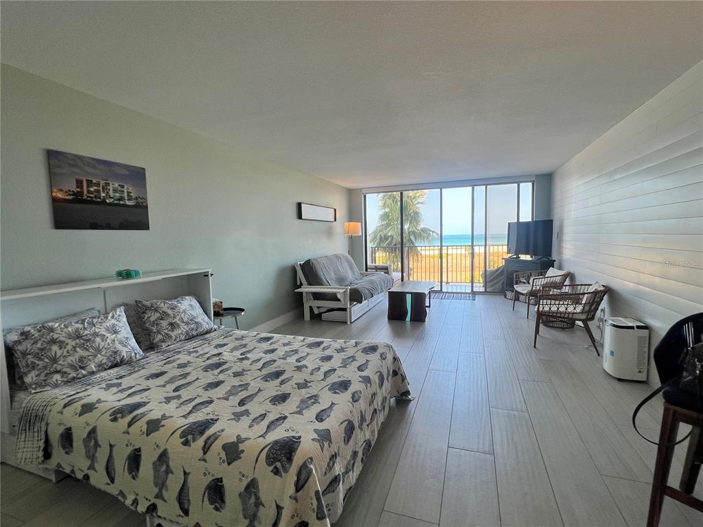 A studio apartment features a bed, sofa, and floor-to-ceiling windows overlooking the ocean — 1250 GULF BOULEVARD UNIT 405, CLEARWATER, FL