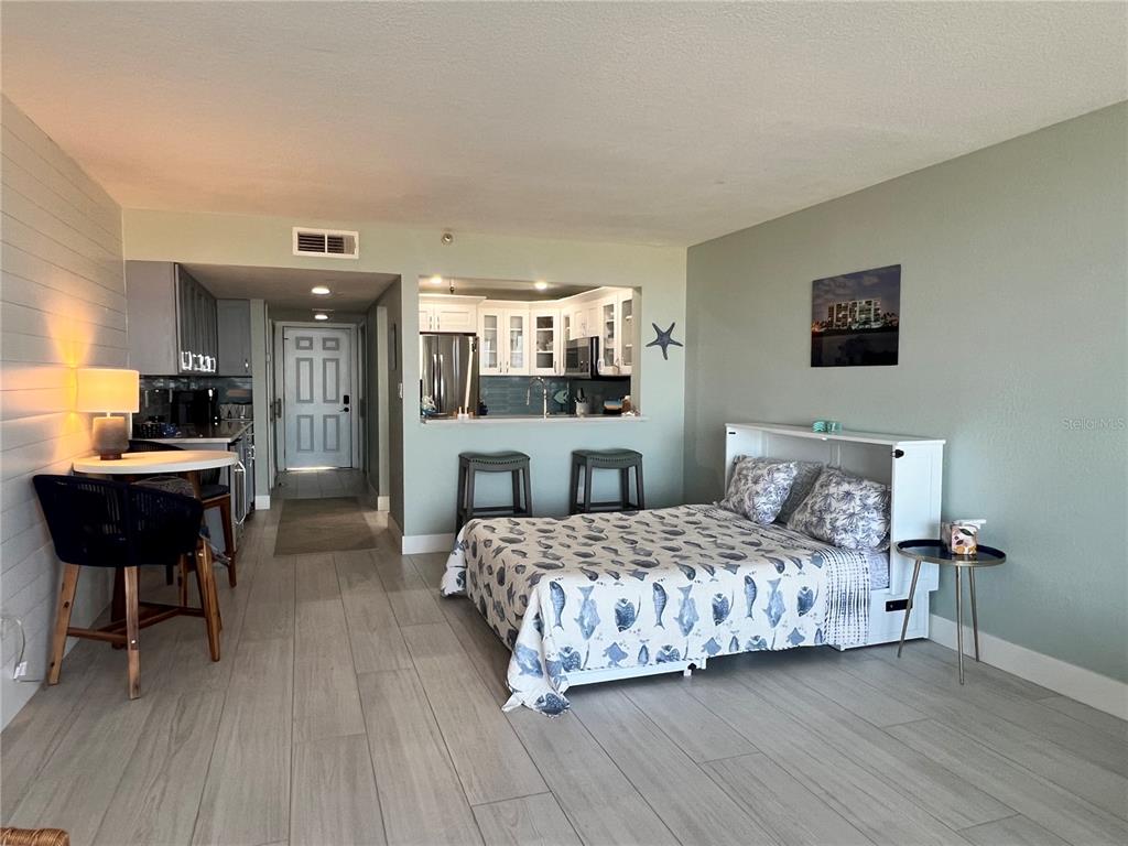 A studio apartment features a kitchen with a breakfast bar, a bed, and tile flooring — 1250 GULF BOULEVARD UNIT 405, CLEARWATER, FL