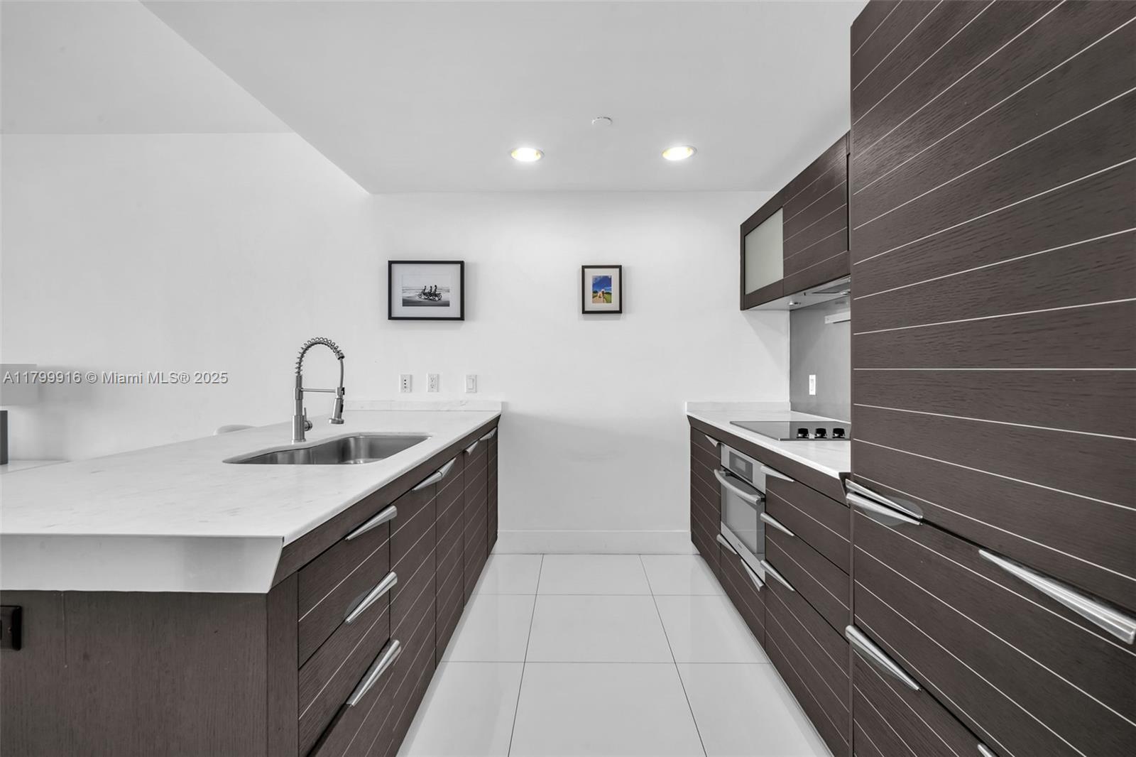 A modern kitchen features dark wood cabinetry, white countertops, and stainless steel appliances — 200 Biscayne Boulevard Way # 4012, Miami FL 33131, MIAMI, FL