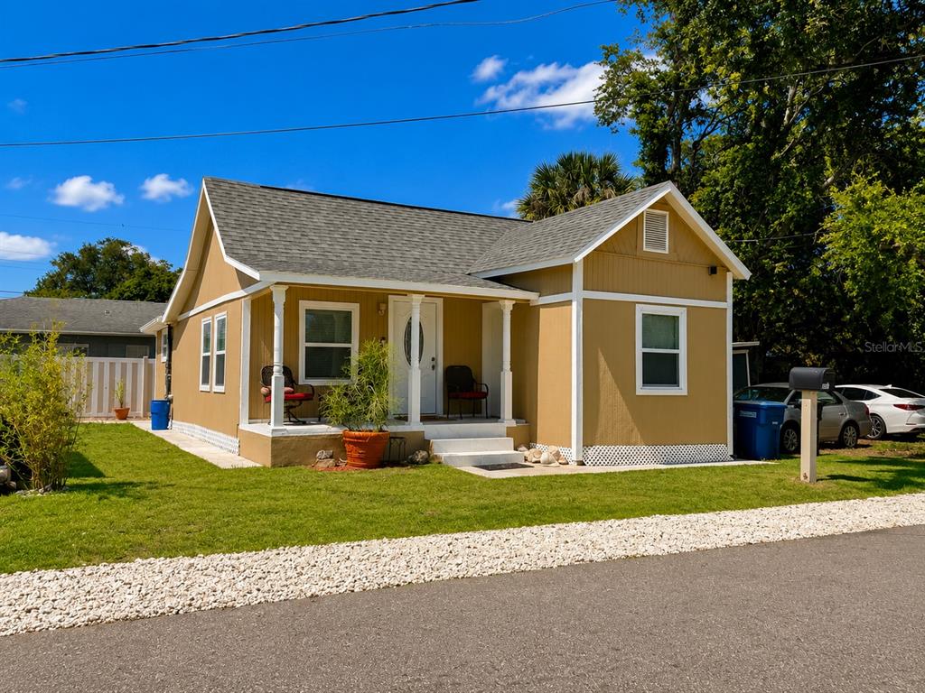 A tan, single-story house with a front porch, white trim, and a gray shingled roof — 802 JURGENS STREET, CLEARWATER, FL