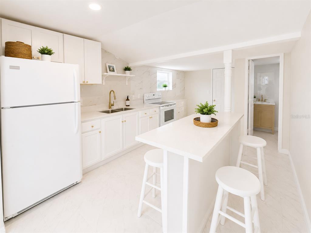 A bright, white kitchen features a central island, stainless steel appliances, and marble-look countertops — 802 JURGENS STREET, CLEARWATER, FL
