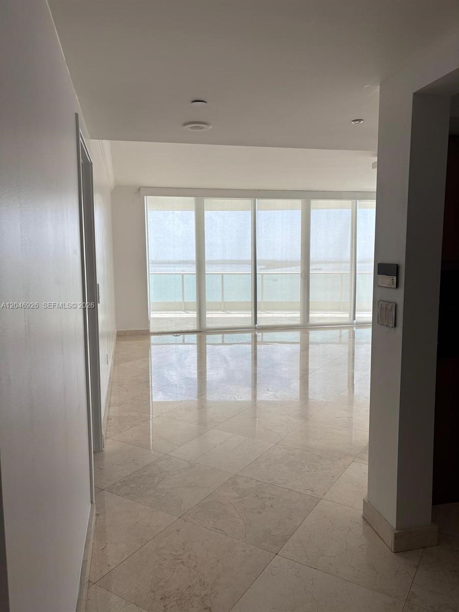 An empty room features light-colored tile flooring and floor-to-ceiling windows overlooking the water — 1331 Brickell Bay Dr # 1911, Miami FL 33131, MIAMI, FL