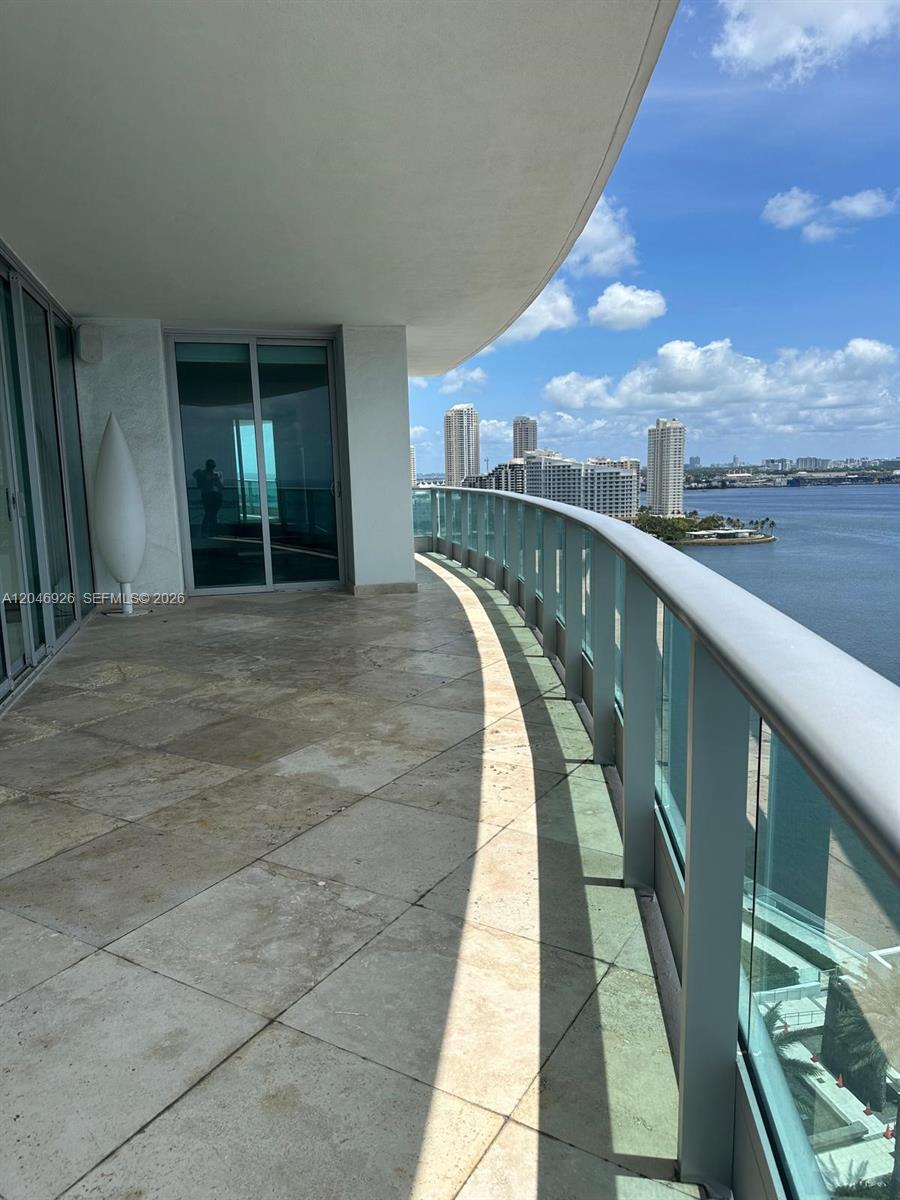 A curved balcony with stone flooring overlooks a bay and city skyline — 1331 Brickell Bay Dr # 1911, Miami FL 33131, MIAMI, FL