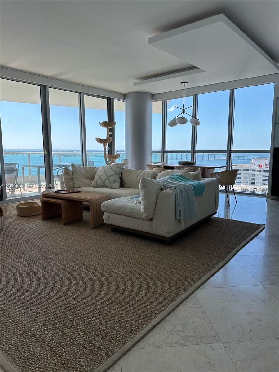 A living room features a white sectional sofa, a woven coffee table, and floor-to-ceiling windows — 1331 Brickell Bay Dr # 1911, Miami FL 33131, MIAMI, FL