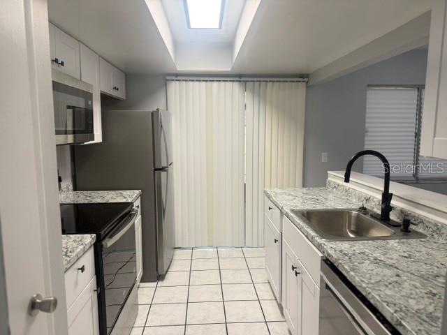 A kitchen features white cabinets, granite countertops, stainless steel appliances, and a skylight — 5301 PINEBURY COURT, ORLANDO, FL