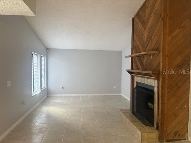 A living room with light gray walls, tile flooring, and a wood-paneled fireplace — 5301 PINEBURY COURT, ORLANDO, FL