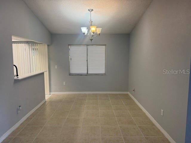 A dining area with light gray walls, tile flooring, and a central chandelier — 5301 PINEBURY COURT, ORLANDO, FL