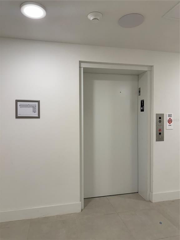 A white elevator door is centered in a hallway with a floor plan sign nearby — 5592 NE PGA BOULEVAR UNIT #314, ORLANDO, FL