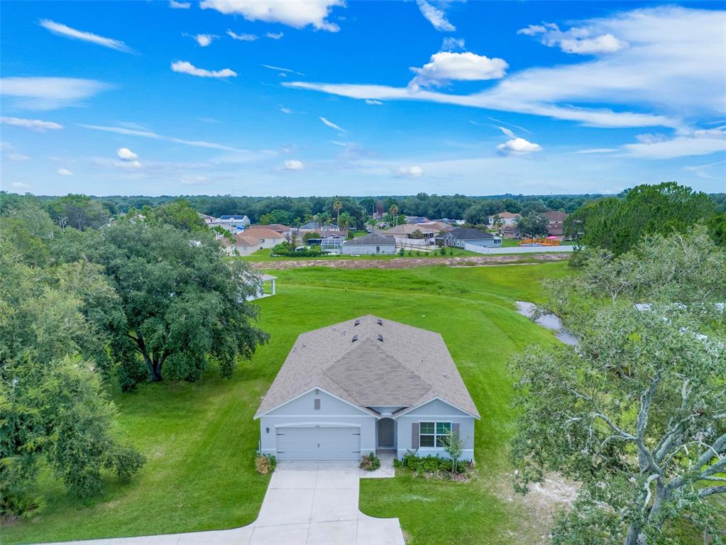 An aerial view of a single-story suburban house with a concrete driveway and large yard — 658 COTULLA DRIVE, KISSIMMEE, FL