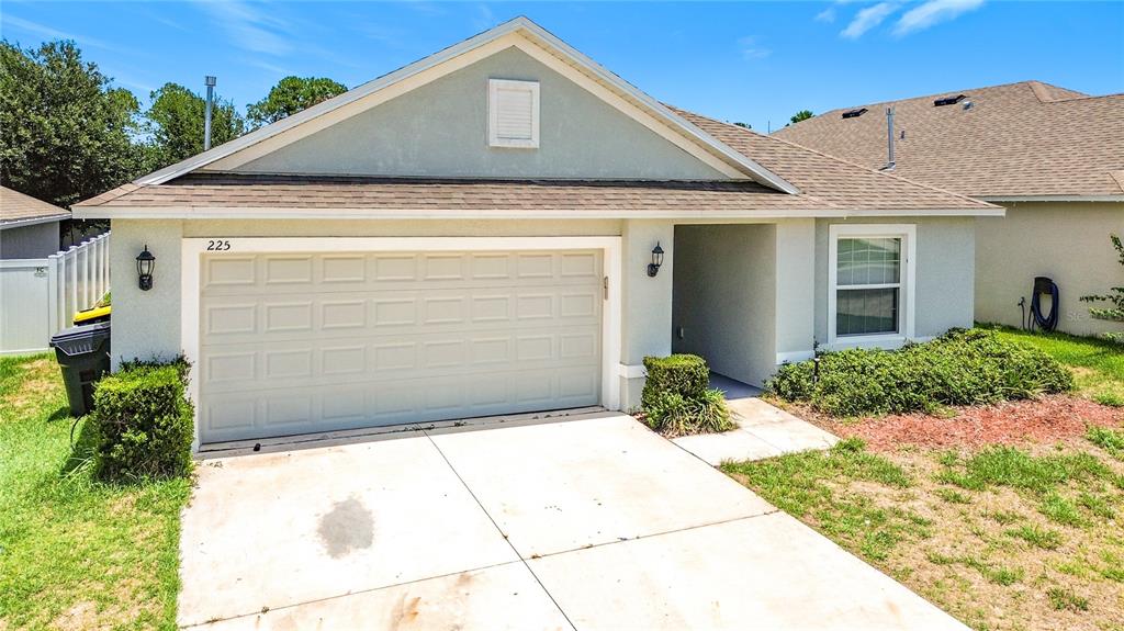 A single-story house with a beige garage, a concrete driveway, and a small front yard — 225 BELLA VERANO WAY, DAVENPORT, FL