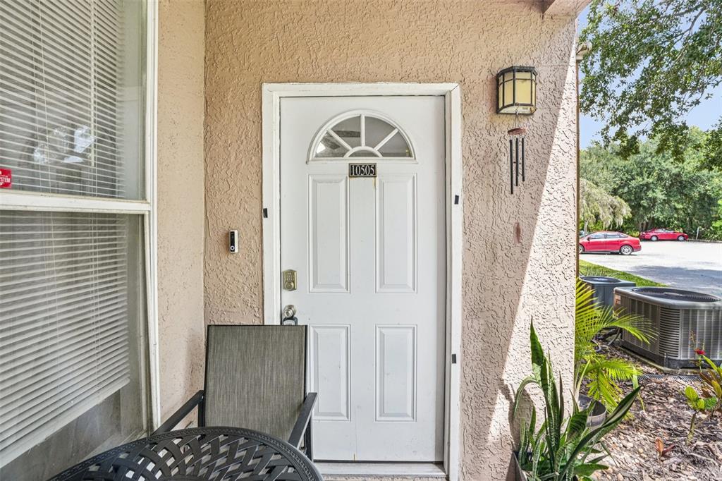 A white front door with a number plate sits on a covered porch with stucco walls — 10505 VILLA VIEW CIRCLE, TAMPA, FL