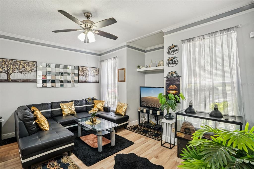 A living room features a black sectional sofa, a glass coffee table, and a ceiling fan — 10505 VILLA VIEW CIRCLE, TAMPA, FL