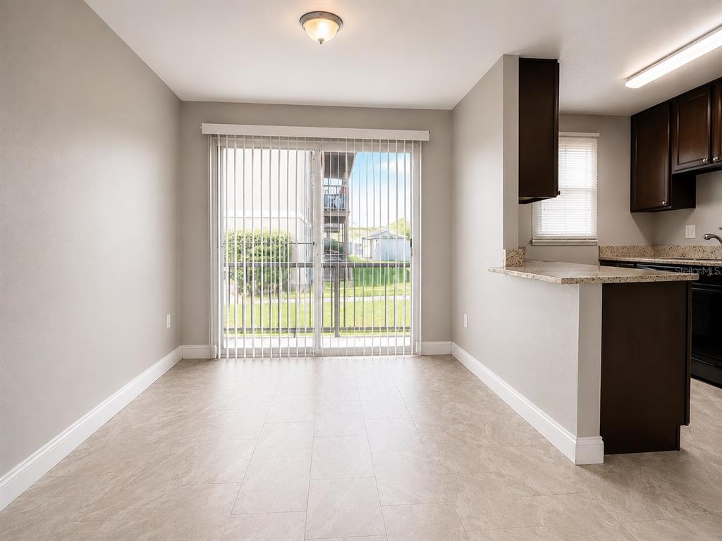 A dining area with tile flooring, a sliding glass door, and an adjacent kitchen counter — 2789 L B MCLEOD ROAD UNIT 2789B, ORLANDO, FL