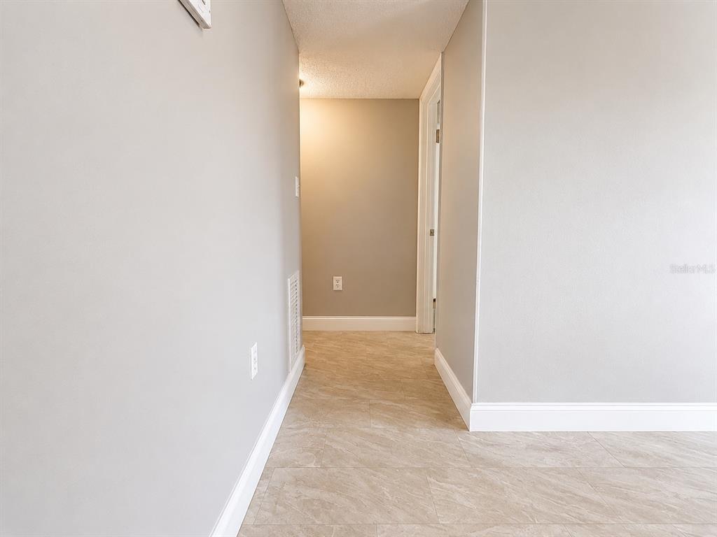 A hallway with light-colored tile flooring and neutral gray walls leads toward a doorway — 2789 L B MCLEOD ROAD UNIT 2789B, ORLANDO, FL