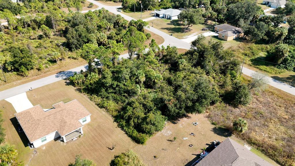 An aerial view shows a wooded residential lot situated between two houses and paved roads — FIELDING STREET, NORTH PORT, FL