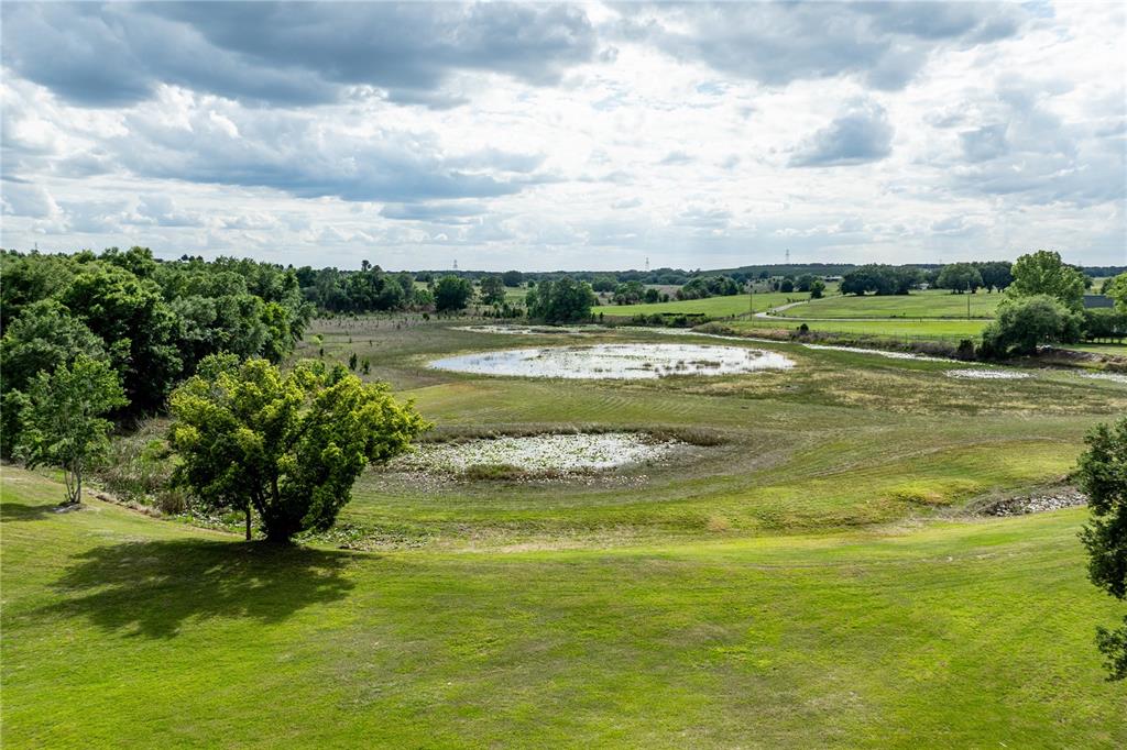An elevated view of a grassy field with two small ponds and surrounding trees — 25101 TURKEY LAKE ROAD, HOWEY IN THE HILLS, FL