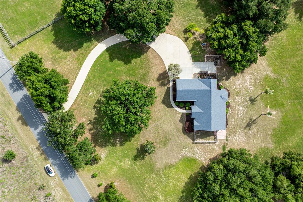 An aerial view shows a house with a curved driveway surrounded by trees and grass — 25101 TURKEY LAKE ROAD, HOWEY IN THE HILLS, FL