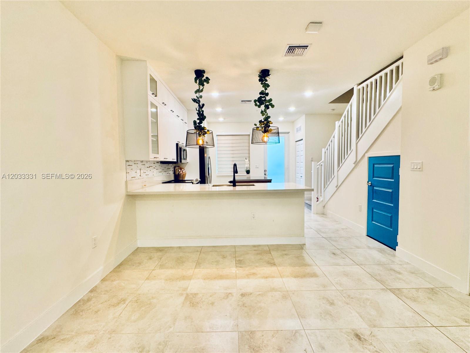 A kitchen with white cabinets, a breakfast bar, and a bright blue door — 10295 NW 64th Ter # 104, Doral FL 33178, DORAL, FL