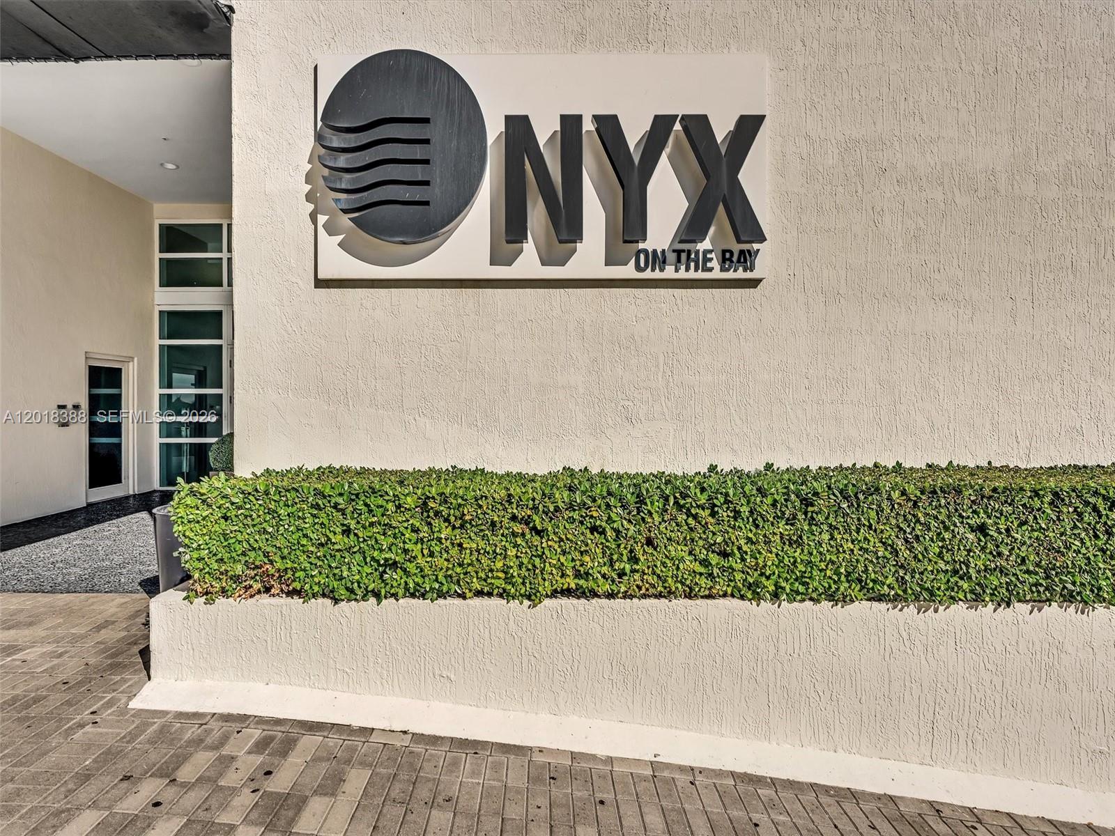 The exterior wall features a large sign for Onyx on the Bay above a hedge — 665 NE 25th St # 1404, Miami FL 33137, MIAMI, FL