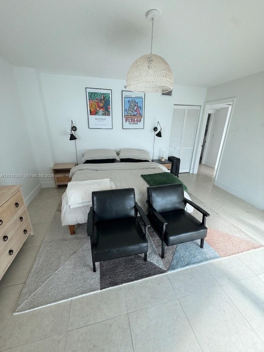 A bedroom features a bed with two black chairs on a geometric rug — 665 NE 25th St # 1404, Miami FL 33137, MIAMI, FL