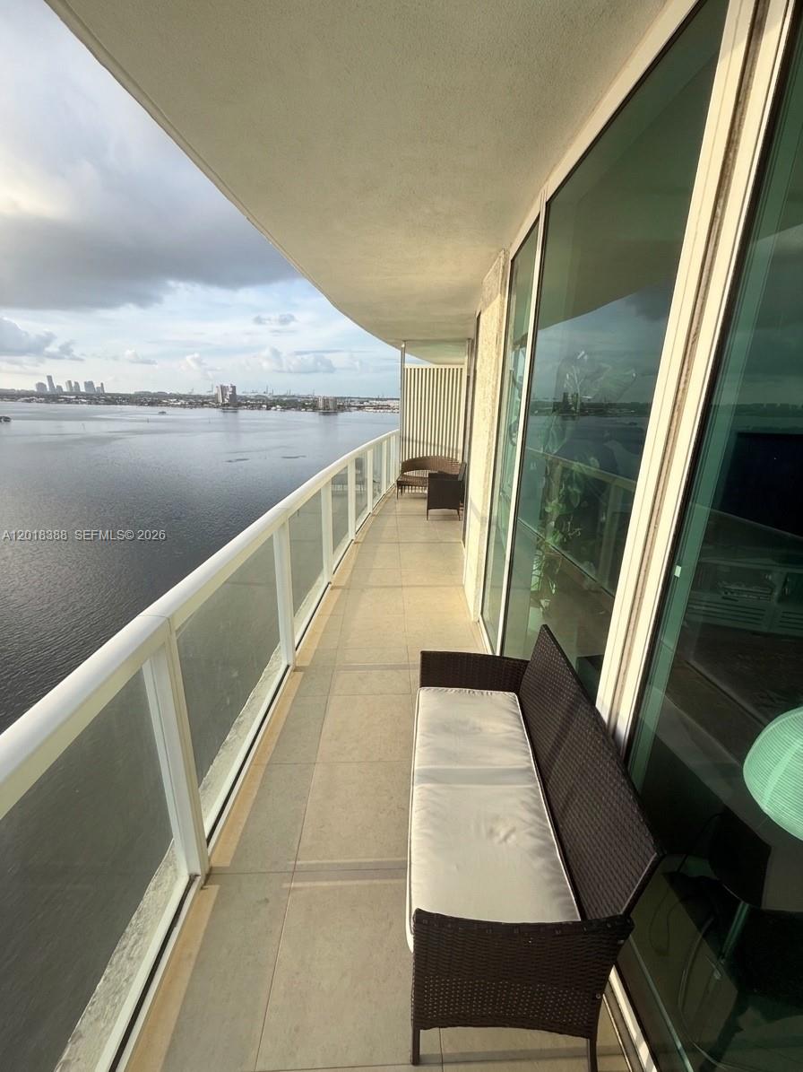 A balcony with a glass railing overlooks a large body of water and city skyline — 665 NE 25th St # 1404, Miami FL 33137, MIAMI, FL