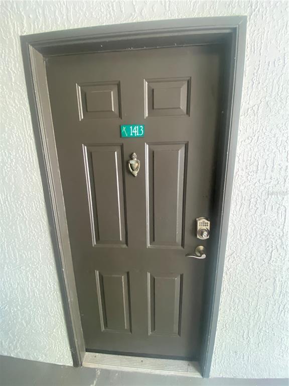 A dark brown, four-panel entry door with a door knocker and electronic keypad lock — 13838 FAIRWAY ISLAND DRIVE UNIT 1413, ORLANDO, FL