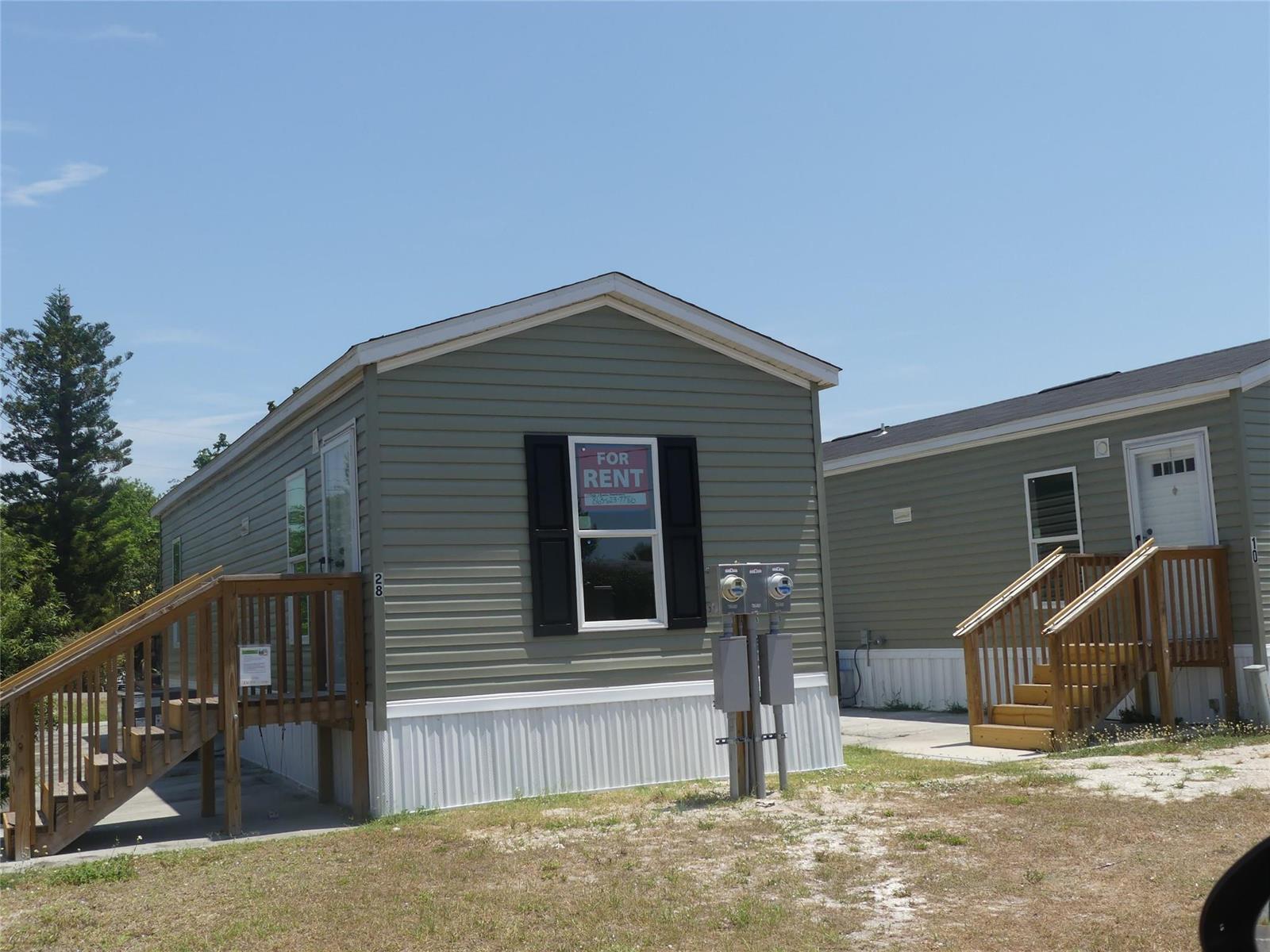 Two light green manufactured homes with wooden stairs and a for rent sign — 8791 Highway 78, Okeechobee FL 34971, OKEECHOBEE, FL