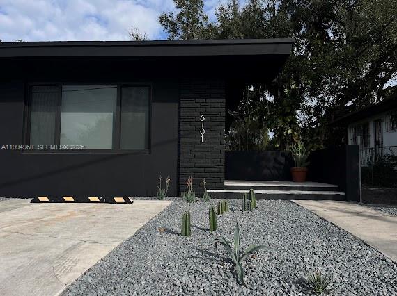 A modern house exterior features black walls, a stone accent pillar, and a gravel front yard — 6101 NE Miami Ct # 2, Miami FL 33137, MIAMI, FL