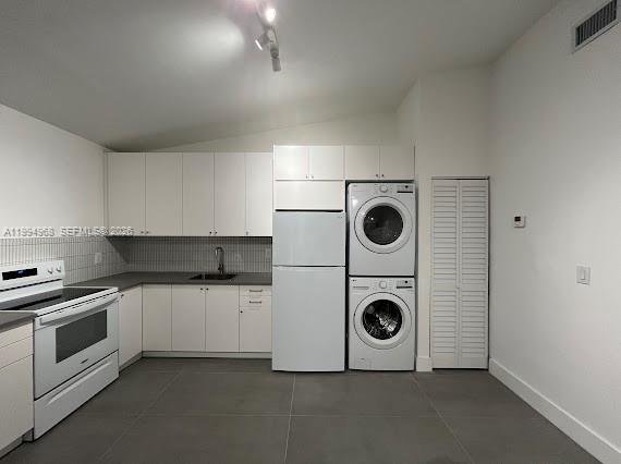 A kitchen features white cabinetry, stainless steel appliances, a stacked washer-dryer, and gray tile flooring — 6101 NE Miami Ct # 2, Miami FL 33137, MIAMI, FL