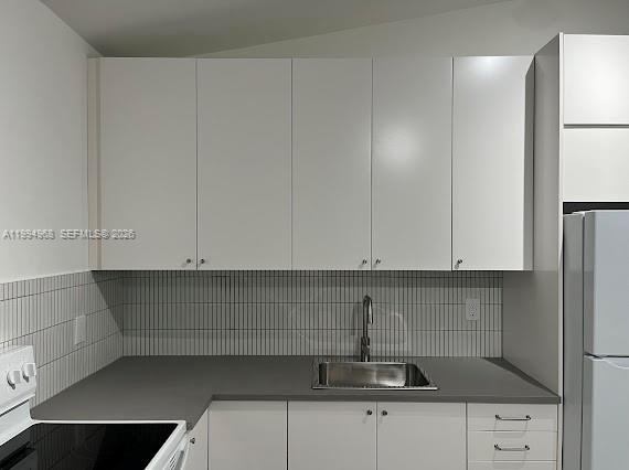 A kitchen features white cabinets, a dark gray countertop, a stainless steel sink, and tiled backsplash — 6101 NE Miami Ct # 2, Miami FL 33137, MIAMI, FL