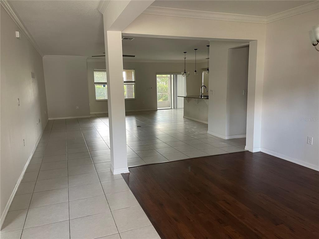 An open-concept living area features a dark wood floor transition to light-colored tile flooring — 1312 RALPH POE DRIVE, APOPKA, FL