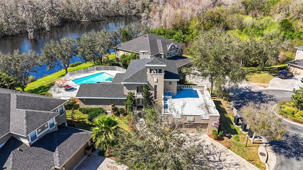 An aerial view shows a multi-story house with a swimming pool and a lake nearby — 7425 TERRACE RIVER DRIVE, TAMPA, FL