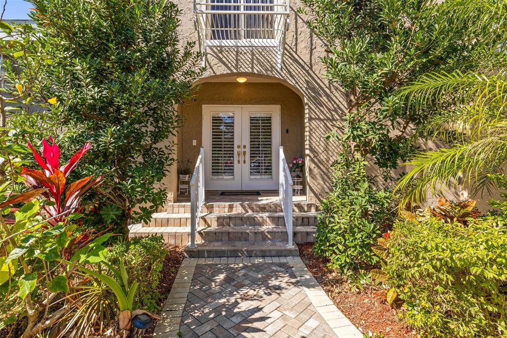 A brick walkway leads to the double glass front doors of a stucco home — 7425 TERRACE RIVER DRIVE, TAMPA, FL