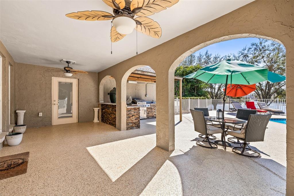 A covered patio features a stone outdoor kitchen, dining set, and ceiling fans — 7425 TERRACE RIVER DRIVE, TAMPA, FL