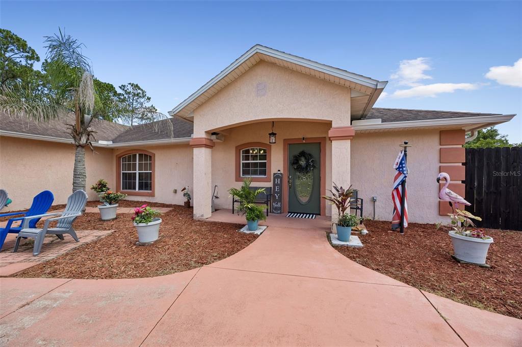 The exterior of a single-story house features a covered entryway, a walkway, and potted plants — 134 BOWFIN DRIVE, PALATKA, FL