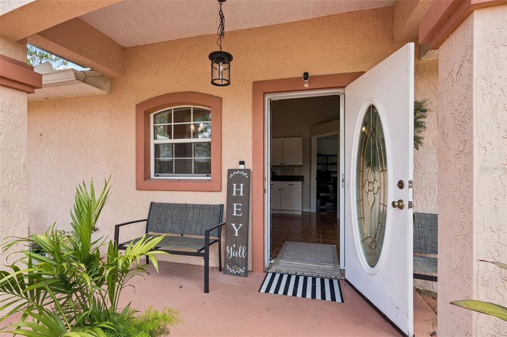 A covered front porch features a bench, a decorative sign, and an open front door — 134 BOWFIN DRIVE, PALATKA, FL