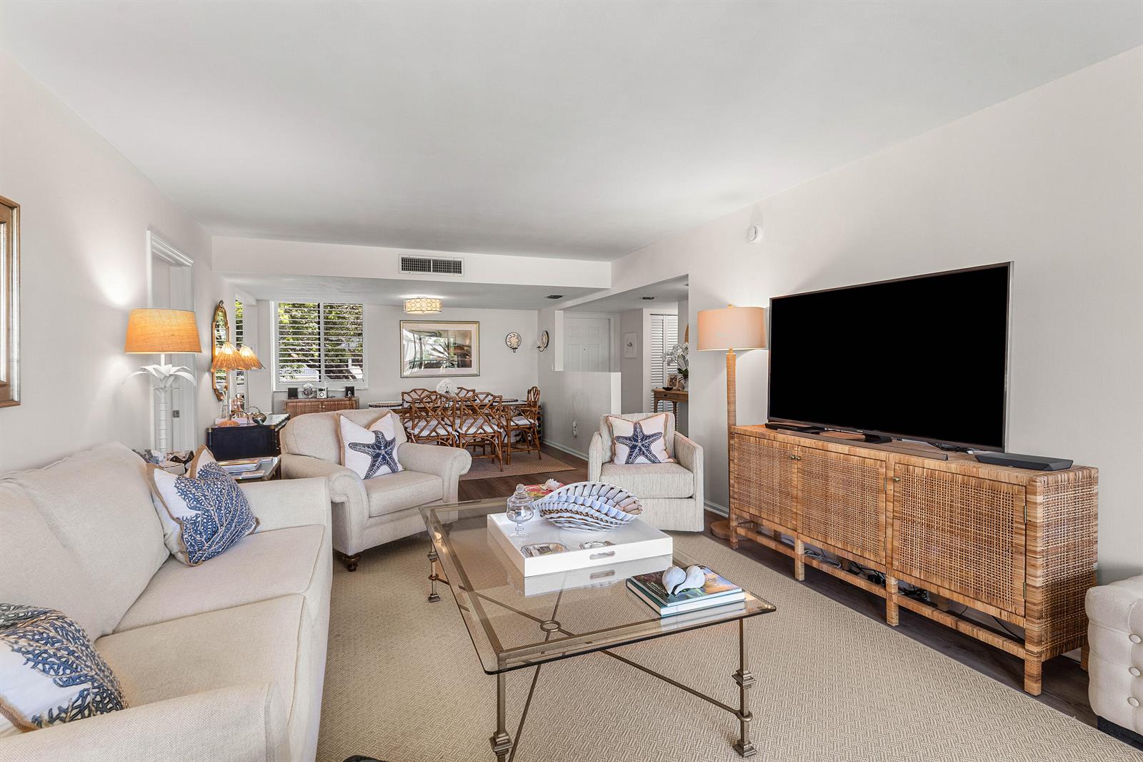 A living room with a beige sofa, two armchairs, a glass coffee table, and television — 1605 S Us Highway 1, Jupiter FL 33477, JUPITER, FL