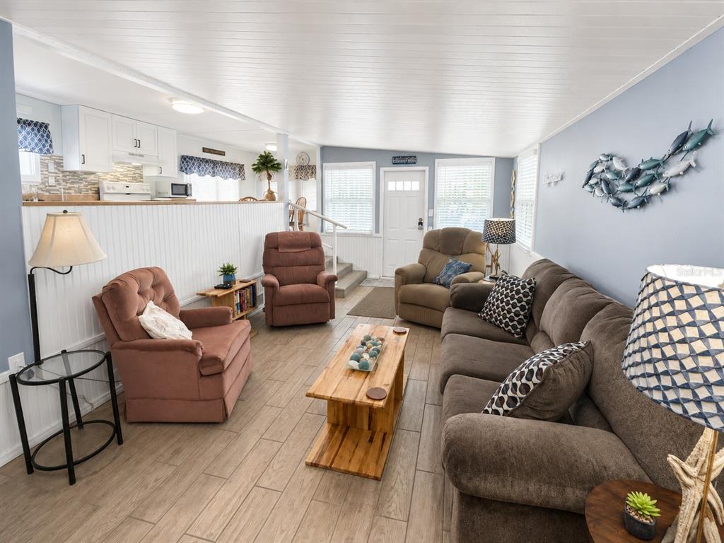 A living room features light wood-look tile flooring, a brown sofa, and two recliner chairs — 1907 IOWA AVENUE, BRADENTON, FL