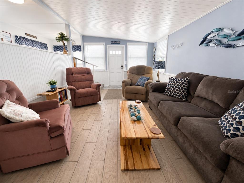 A living room features a brown sofa, two recliners, a wooden coffee table, and tile flooring — 1907 IOWA AVENUE, BRADENTON, FL